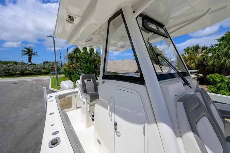 Slide: The Image of 2023 Regulator 28 boat with sleek design, featuring helm station and seating, under clear blue sky. - 24