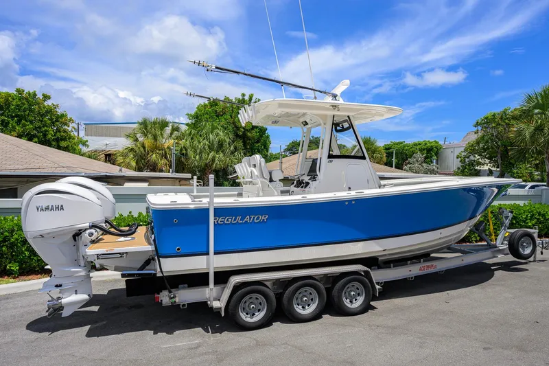 Slide: The Image of 2023 Regulator 28 boat with Yamaha engines on a trailer, parked outdoors. - 4
