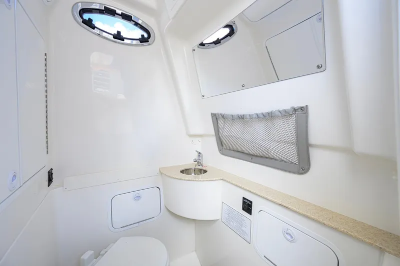 Slide: The Image of 2023 Regulator 28 boat interior with compact bathroom, featuring sink and storage. - 51