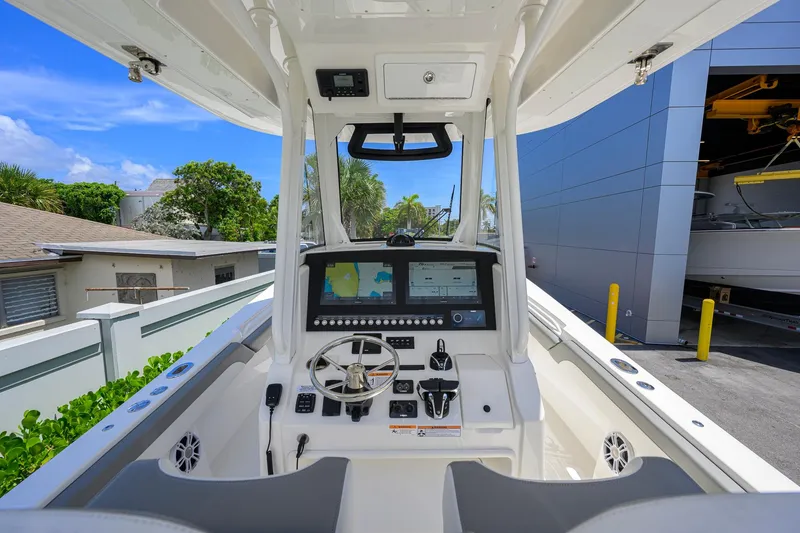Slide: The Image of 2023 Regulator 28 boat cockpit with advanced navigation system and steering wheel, docked outdoors. - 9