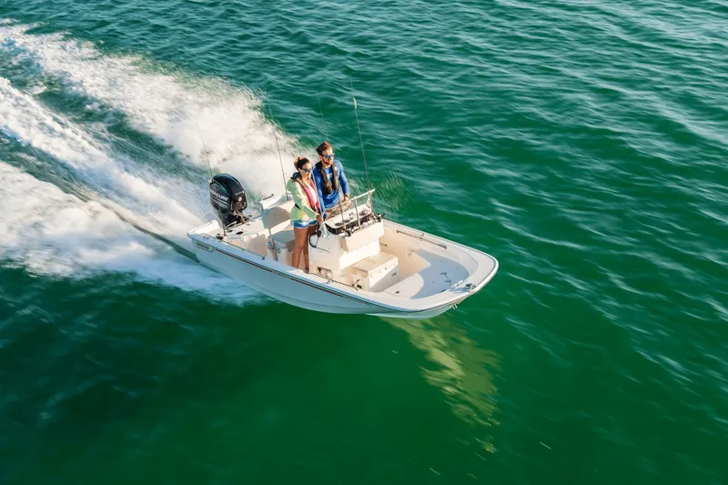Slide: The Image of A 2027 Boston Whaler 150 Montauk speeds across green water with three people on board. - 13