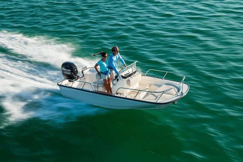 Slide: The Image of A 2027 Boston Whaler 150 Montauk boat speeds across the water with two people on board. - 2