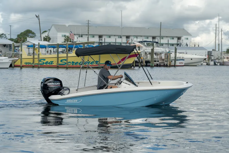 Slide: The Image of A man drives a blue and white motorboat with a black sunshade on calm water. - 4