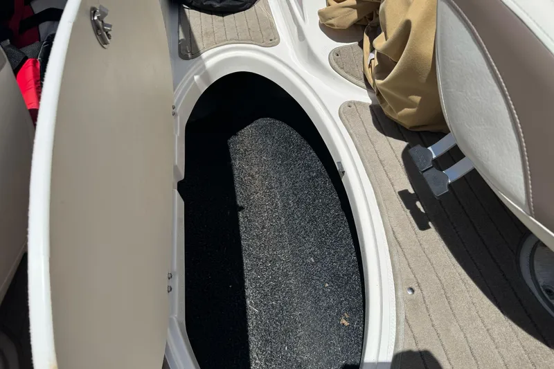 Slide: The Image of 2009 Glastron GLS 215 boat interior storage compartment with open hatch and carpeted flooring. - 21