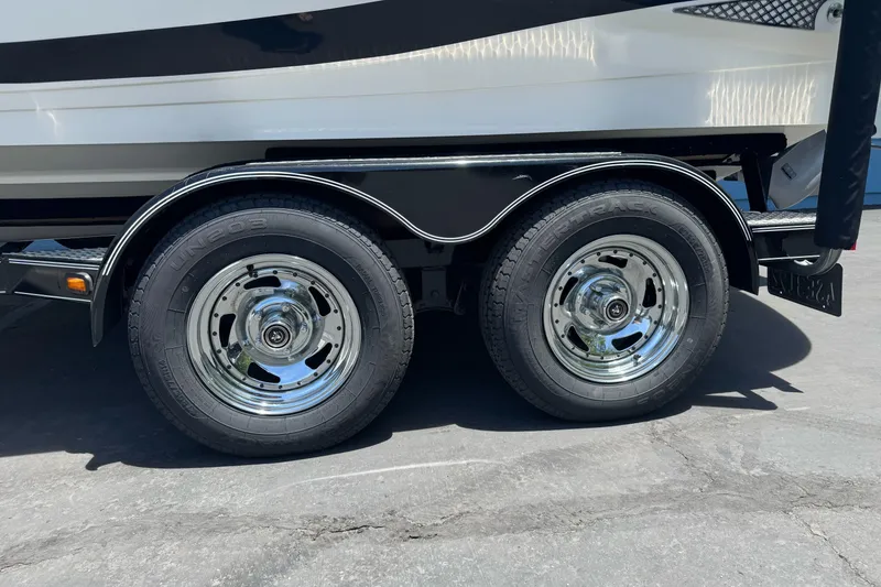 Slide: The Image of 2009 Glastron GLS 215 boat trailer with dual chrome wheels on pavement. - 23