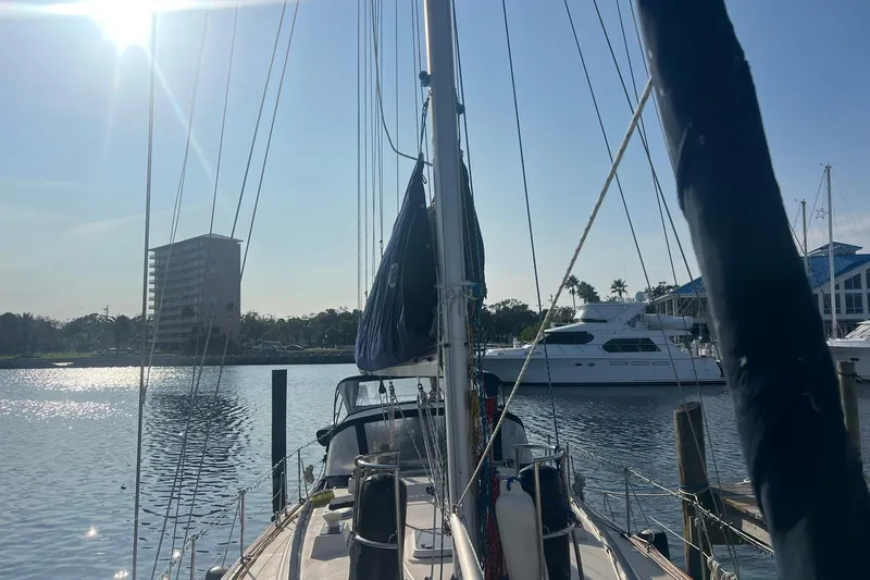 Slide: The Image of 1994 Island Packet 44 cutter sailboat docked in sunny marina with buildings in background. - 10