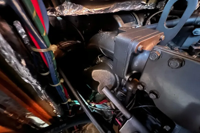 Slide: The Image of Engine compartment of a 1994 Island Packet 44 cutter sailboat, showing wiring and mechanical components. - 114