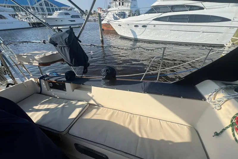 Slide: The Image of 1994 Island Packet 44 cutter sailboat cockpit with marina view, featuring cushioned seating. - 23