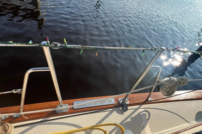 Slide: The Image of 1994 Island Packet 44 cutter sailboat deck with festive lights and water reflection. - 28