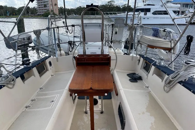 Slide: The Image of 1994 Island Packet 44 cutter sailboat cockpit with wooden table and marina view. - 46