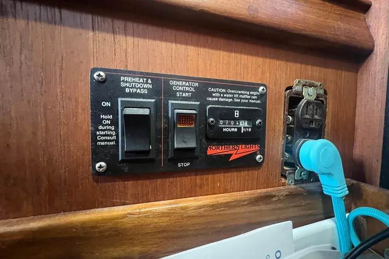 Slide: The Image of Control panel on a 1994 Island Packet 44 cutter sailboat, featuring generator controls. - 85