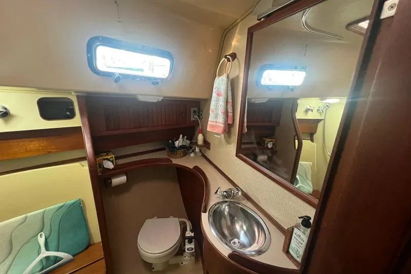 Slide: The Image of Bathroom interior of 1994 Island Packet 44 cutter, featuring sink, toilet, and mirror. - 98