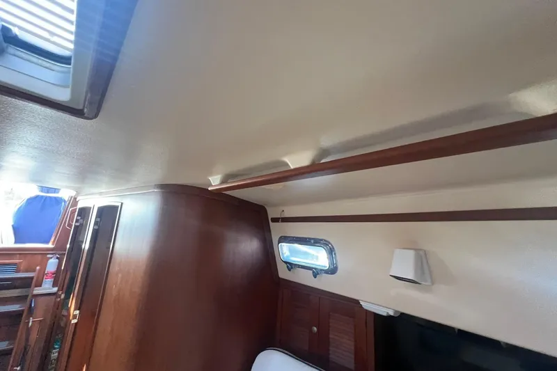 Slide: The Image of Interior of 1994 Island Packet 44 cutter, featuring wood paneling and a porthole window. - 99
