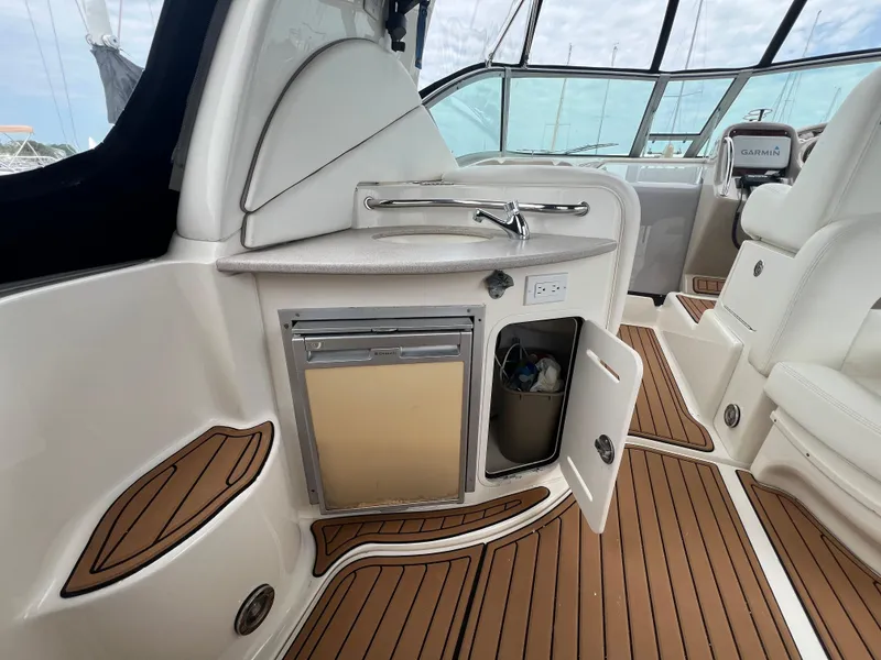 Slide: The Image of 2003 Sea Ray 320 Sundancer cockpit with sink, mini fridge, and teak flooring. - 10