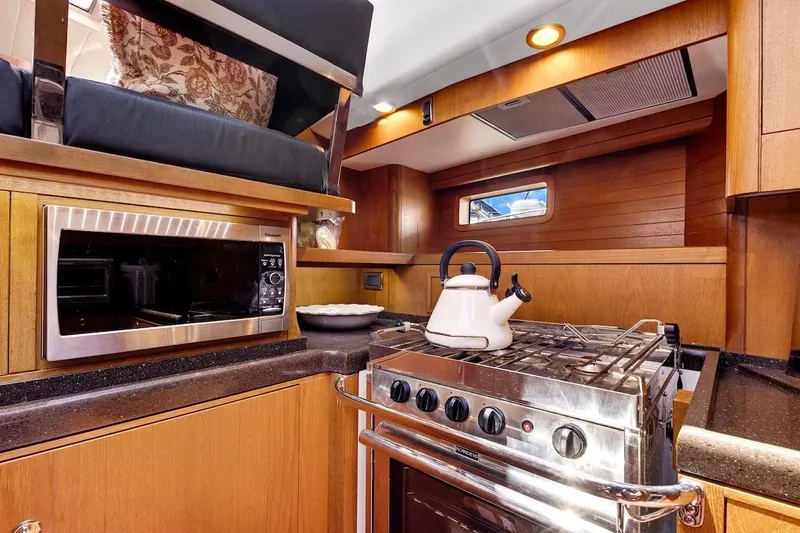 Slide: The Image of Luxurious 2011 Southerly 57 RS yacht kitchen with stove, microwave, and wooden cabinetry. - 35