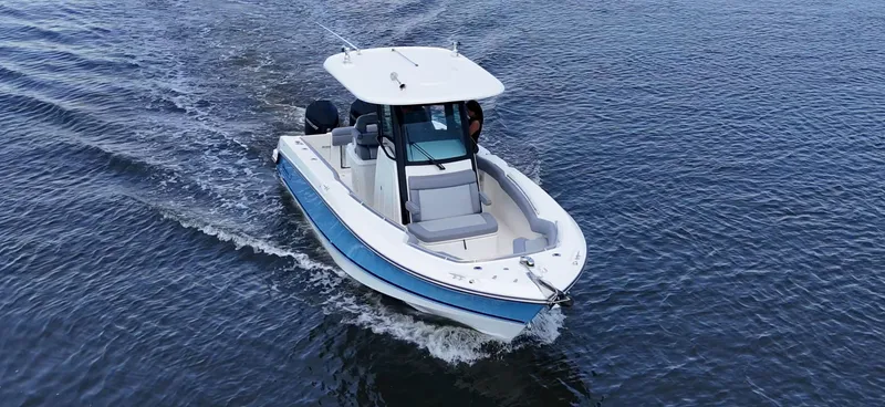 Slide: The Image of A 2027 Boston Whaler 250 Outrage cruising on calm water, featuring a white top and blue accents. - 2