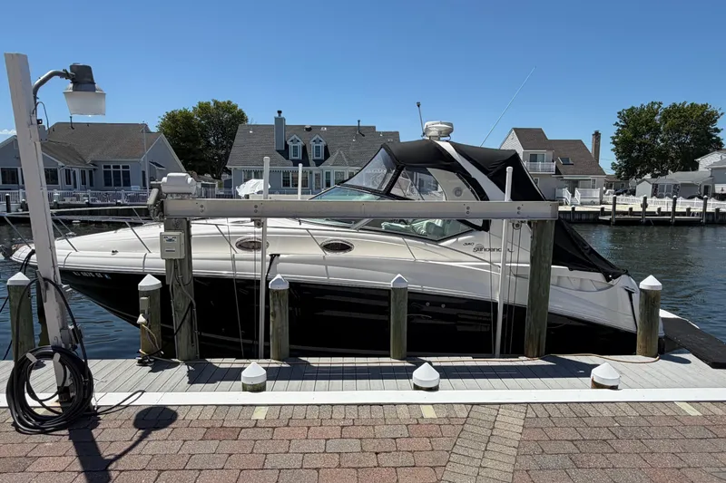 The Image of 2006 Sea Ray Sundancer 320 docked at a marina with waterfront homes in the background. - 0