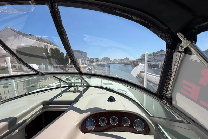 Slide: The Image of 2006 Sea Ray Sundancer 320 cockpit view, overlooking a serene waterfront neighborhood. - 22