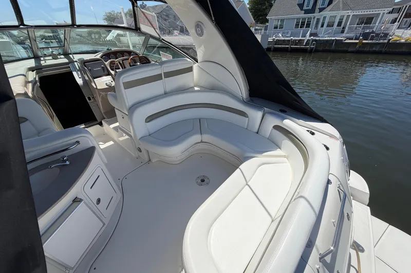 Slide: The Image of 2006 Sea Ray Sundancer 320 boat interior with white seating and helm, docked by water. - 5