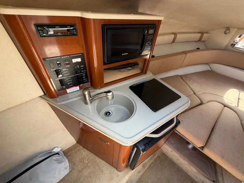 Slide: The Image of Interior of 2011 Sea Ray 240 Sundancer with kitchenette and seating area. - 25
