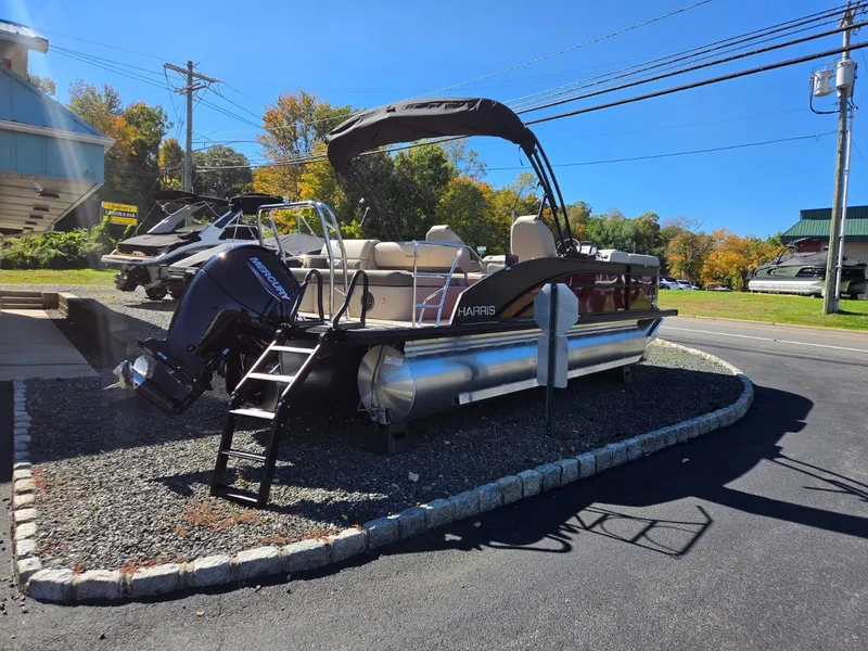 Slide: The Image of 2027 Harris Cruiser 210 pontoon boat with black bimini top and outboard motor, displayed on a lot. - 6