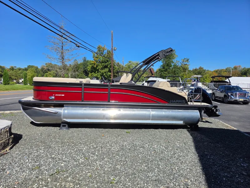 Slide: The Image of A red 2027 Harris Cruiser 210 pontoon boat is parked on a gravel lot. - 1