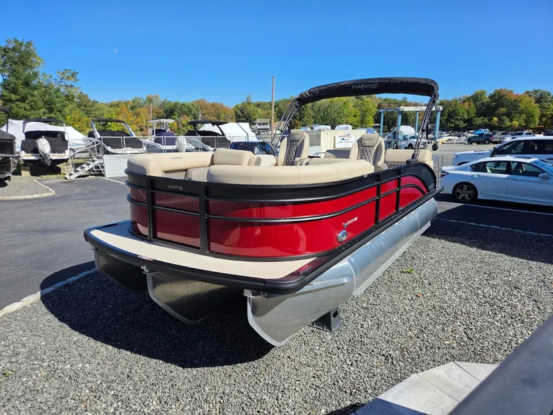 Slide: The Image of A red pontoon boat with beige seating is on a gravel lot. It's a Harris Cruiser 210. - 2