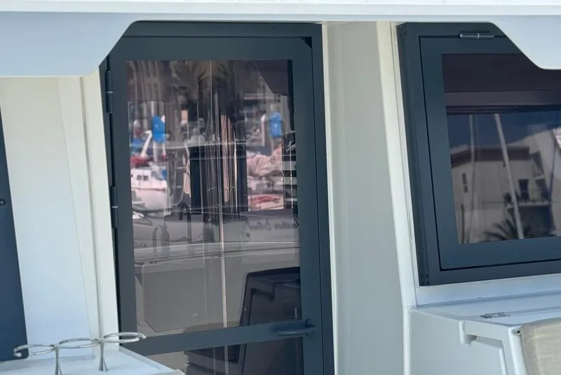 Slide: The Image of Close-up of a 2023 Bali 4.6 yacht window and door, reflecting marina scenery. - 20