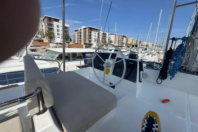 Slide: The Image of Helm of 2023 Bali 4.6 catamaran in marina, surrounded by boats and buildings. - 38