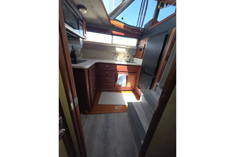 Slide: The Image of Interior of 1986 Bayliner 3888 MY Sedan yacht, featuring a compact kitchen area. - 16
