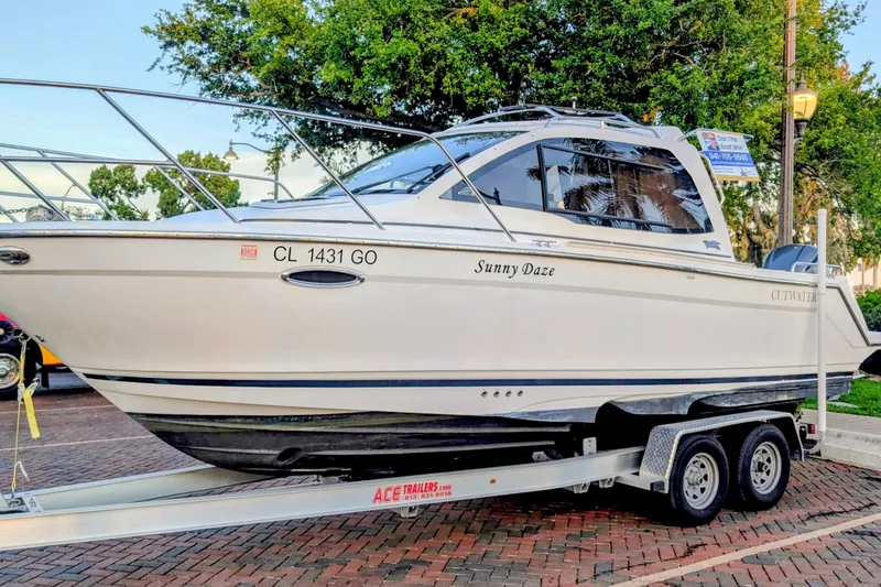 The Image of 2017 Cutwater C-24 Coupe boat on trailer, named "Sunny Daze," parked on brick pavement. - 0