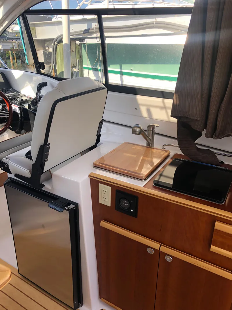 Slide: The Image of Interior of the 2017 Cutwater C-24 Coupe with seat, sink, and wooden cabinets. - 32