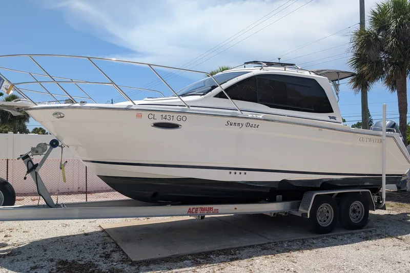 Slide: The Image of 2017 Cutwater C-24 Coupe boat on trailer, named "Sunny Daze," parked outdoors. - 59