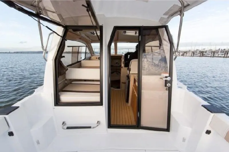 Slide: The Image of 2017 Cutwater C-24 Coupe boat interior with open doors, overlooking a serene marina. - 18