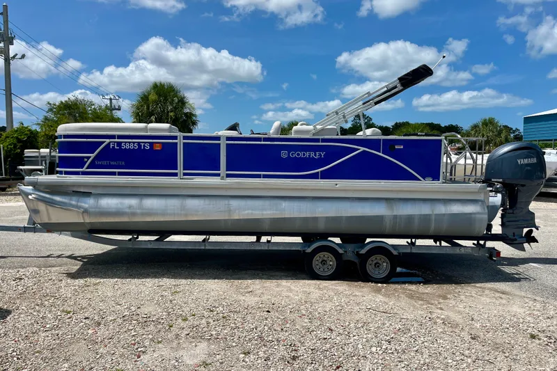 Slide: The Image of 2024 Godfrey Sweetwater 2286 SFL pontoon boat on trailer under blue sky. - 6
