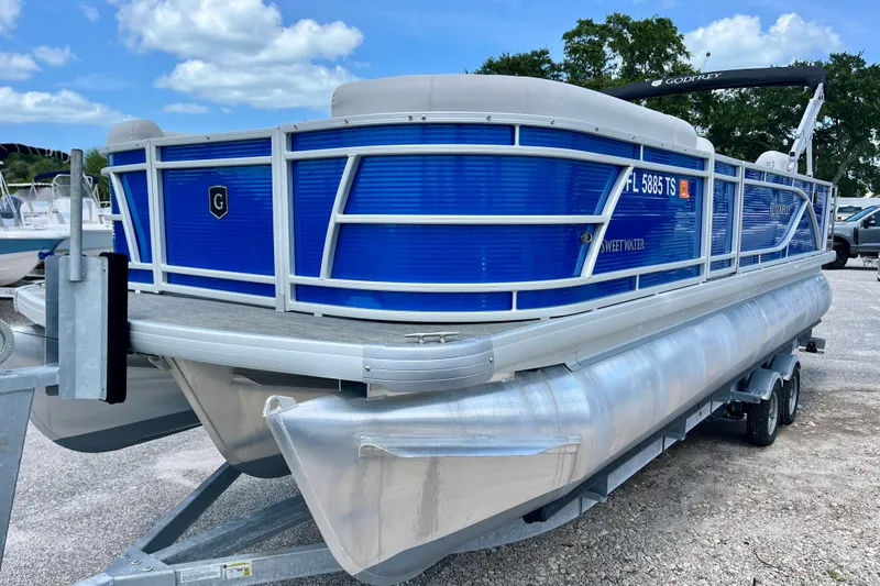 Slide: The Image of 2024 Godfrey Sweetwater 2286 SFL pontoon boat on trailer, blue exterior, parked outdoors. - 7