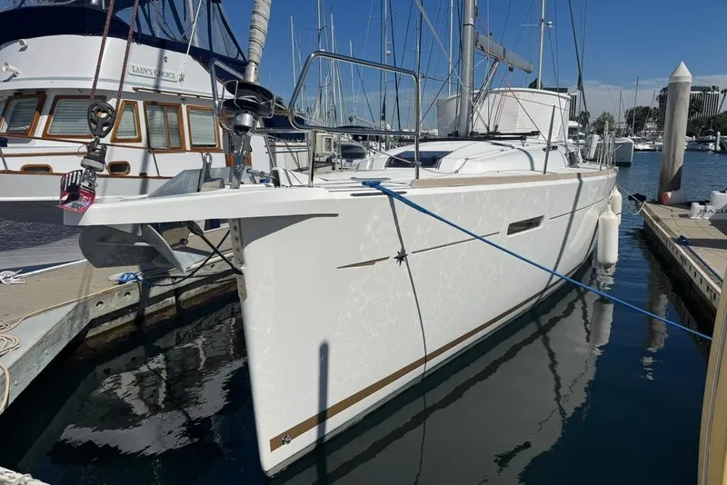 Slide: The Image of 2017 Jeanneau Sun Odyssey 449 sailboat docked in a marina, reflecting on calm water. - 2
