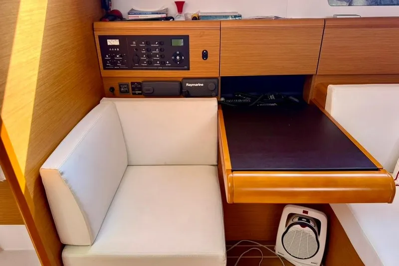 Slide: The Image of Navigation station in 2017 Jeanneau Sun Odyssey 449 yacht with control panel and seating. - 24