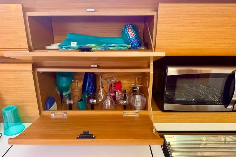 Slide: The Image of Kitchen storage on 2017 Jeanneau Sun Odyssey 449 yacht with glasses and microwave. - 69