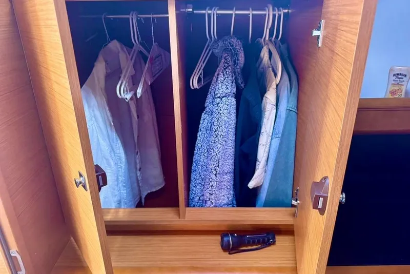 Slide: The Image of Wardrobe inside 2017 Jeanneau Sun Odyssey 449 yacht, featuring hanging clothes and a flashlight. - 71