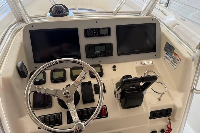 Slide: The Image of 2007 Pursuit C 310 Center Console boat dashboard with steering wheel and navigation controls. - 15