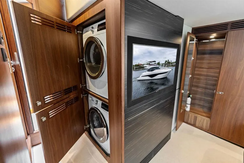Slide: The Image of Luxury yacht interior with washer-dryer, wooden cabinetry, and wall-mounted TV displaying a yacht image. - 72