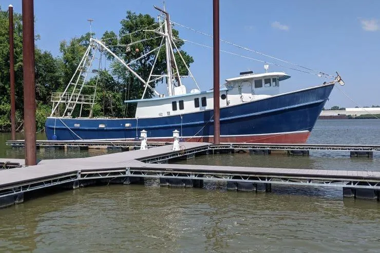 Slide: The Image of 1977 Commercial Expedition Trawler docked at a marina, surrounded by calm water and trees. - 1