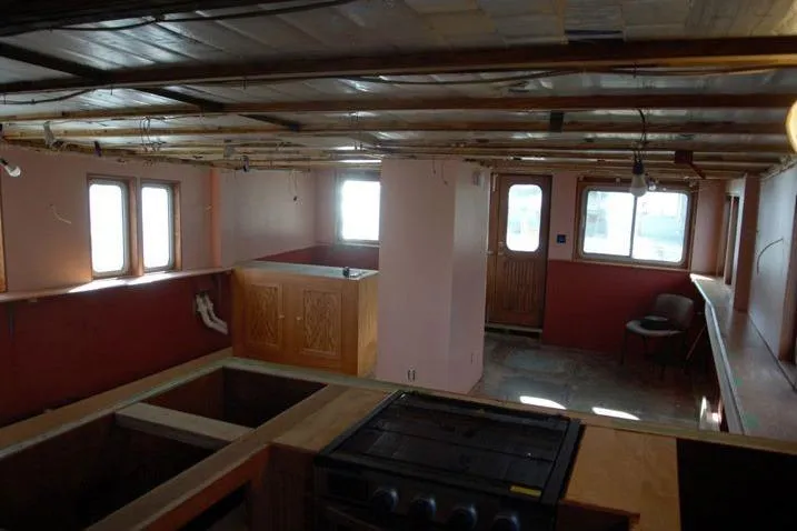 Slide: The Image of Interior of a 1977 Commercial Expedition Trawler with wooden cabinetry and large windows. - 13