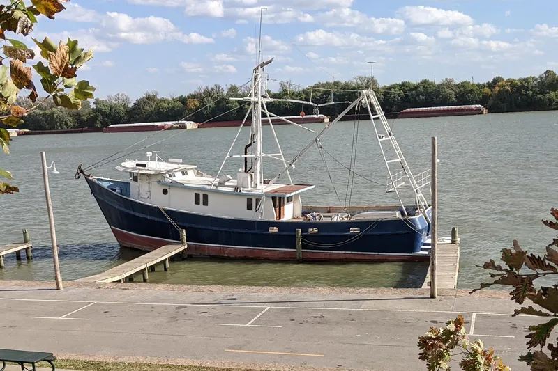 Slide: The Image of 1977 Commercial Expedition Trawler docked by a river, surrounded by trees and clear skies. - 2
