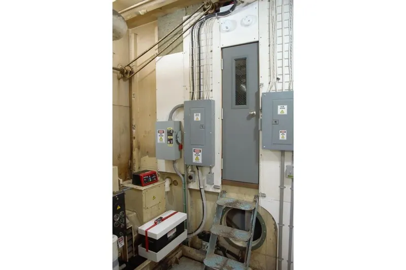 Slide: The Image of Engine room of 1977 Commercial Expedition Trawler with control panels and access door. - 20