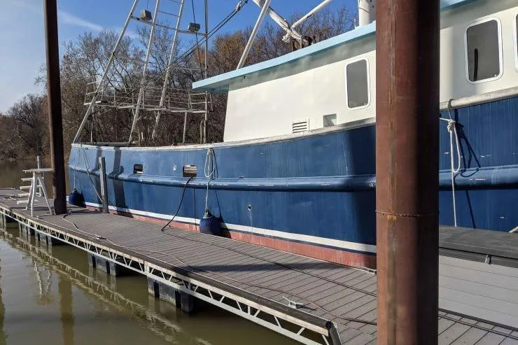 Slide: The Image of 1977 Commercial Expedition Trawler docked at a marina, featuring a blue and white exterior. - 3