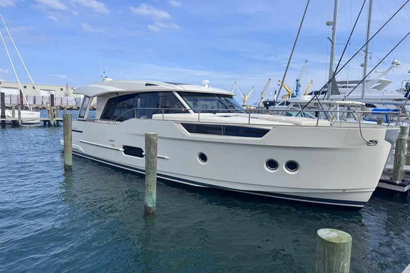 The Image of 2019 Greenline 48 Coupe yacht docked at a marina under a clear blue sky. - 5