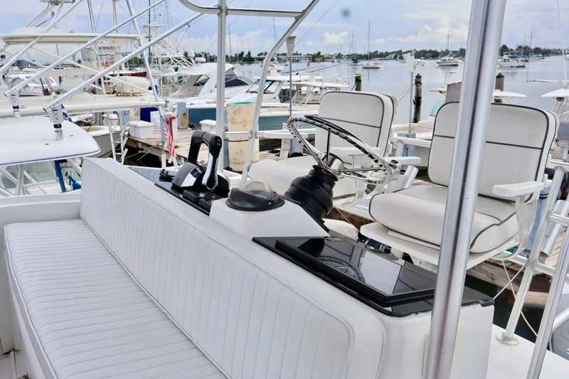 Slide: The Image of 1994 Luhrs 32 Convertible boat helm with white seating and steering wheel at marina. - 57
