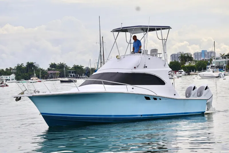 Slide: The Image of 1994 Luhrs 32 Convertible boat cruising in a marina with a person at the helm. - 29